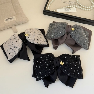 Elegant bow hair clips in tweed and silk fabric with gold charms on a chic background