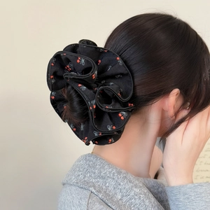 Chouchou en tissu noir avec motifs cerises et nœuds sur le chignon d'un mannequin