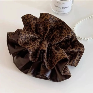 Close-up of leopard print and dark brown faux leather scrunchie with pearls