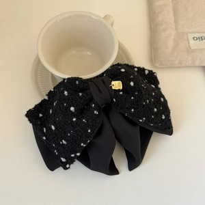 Detail of a large double-layer black tweed bow hair clip with a golden metal charm