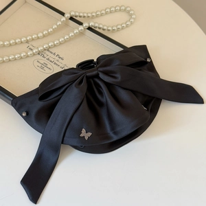 Detailed close-up of a black satin ribbon hair claw clip with rhinestone butterfly accents