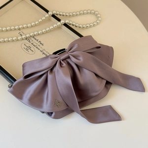 Detailed view of lavender satin bow hair clip featuring a delicate rhinestone butterfly