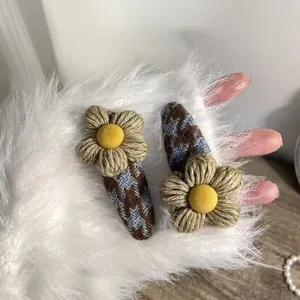 Detailed view of woven floral hair clips with houndstooth fabric and fuzzy pom-pom center
