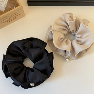 Detail of satin scrunchies in black and champagne gold with elegant pearl pendants