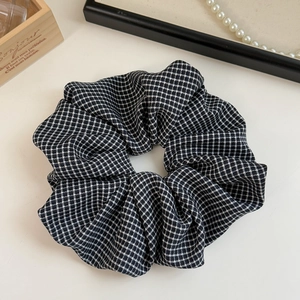Detail of oversized houndstooth scrunchie with soft fabric texture and elegant plaid pattern