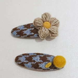 Detail of winter floral hair clips featuring houndstooth pattern and plush flower accents