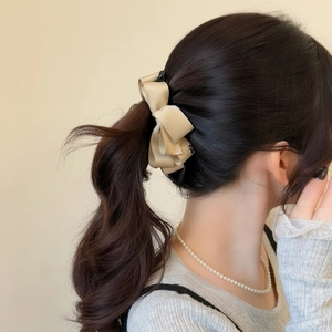 Elegant champagne satin bow hair clip styled on high ponytail for women's hairstyle