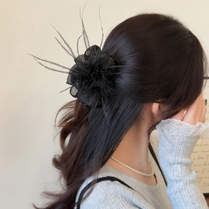 Detail of elegant black feather hair claw with tulle flower and beads for ponytail styling