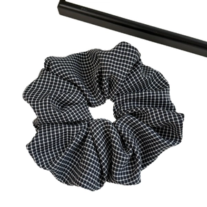 Chic black and white houndstooth hair scrunchie with elastic fabric texture on white background