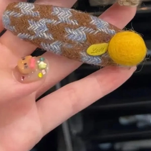 Detail of houndstooth plaid fabric hair clip with yellow pompom and Love tag