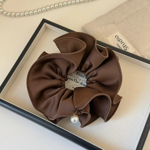 Detail of brown satin scrunchie with ruffled edges and elegant faux pearl pendant