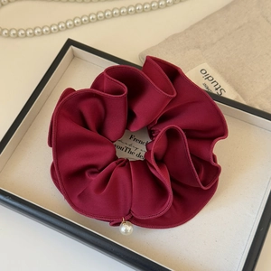 Close-up of burgundy satin scrunchie with edge stitching and pearl pendant detail