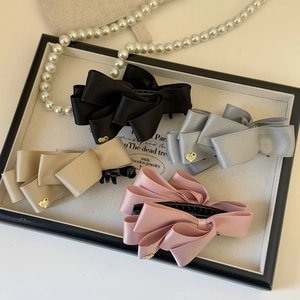 Detailed view of satin bow banana clips in four colors with gold heart charm accents