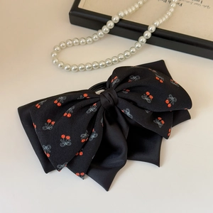 Dettaglio di un grande elastico per capelli nero con stampa a ciliegie in morbido chiffon
