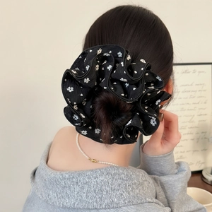Close-up of black floral scrunchie worn on a hair bun showing fabric texture