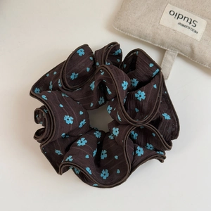 Dettaglio dell'elastico per capelli marrone scuro in chiffon con piccoli fiori azzurri