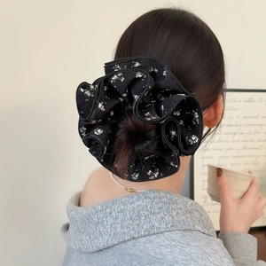 Detail of oversized black floral scrunchie worn in a ponytail for voluminous hair styling