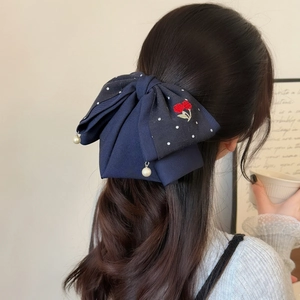 Navy blue bow hair claw clip with floral embroidery and white pearl pendants on model