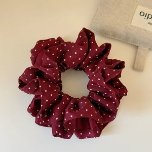 Close-up of burgundy polka dot scrunchie with silk-like fabric texture and elegant folds