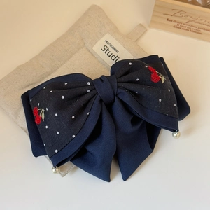 Detail of dark blue bow hair clip with cherry embroidery and white pearl pendants