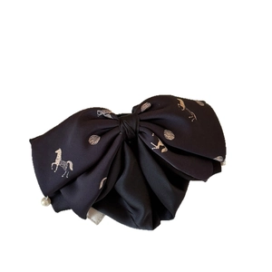 Elegant black satin bow hair clip featuring a vintage horse motif and white pearl detail