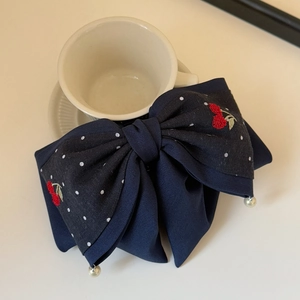 Detail of navy blue bow hair claw clip with cherry embroidery and white pearls