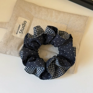 Detailed view of navy blue polka dot and plaid patchwork scrunchie on linen backdrop