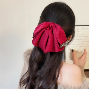 Elegante fermaglio per capelli bordeaux con fiocco di seta e strass su lunghi capelli castani