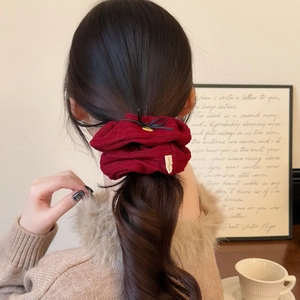 Elegant wine red scrunchie with bow detail worn on low ponytail by model