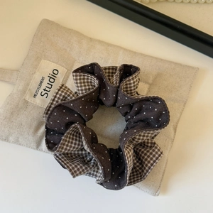 Close-up of brown polka dot and plaid pattern fabric on a puffy oversized scrunchie