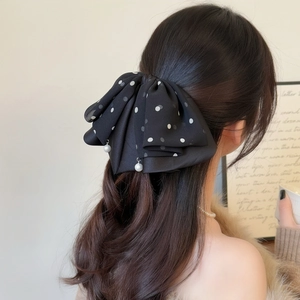 Elegant black polka dot ribbon hair claw clip with pearl pendants shown on ponytail