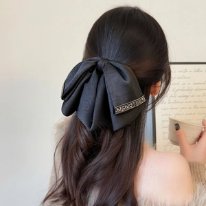 Grande fermaglio per capelli con fiocco nero e strass indossato su una mezza coda alta