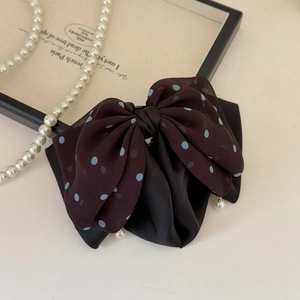 Detail of elegant black mesh polka dot bow hair claw with hanging pearl accents