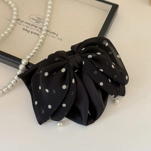 Close-up of black polka dot ribbon hair claw with elegant pearl pendant detail