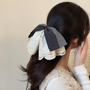 Detailed shot of French lace bow hair clip with navy dots and pearl pendant detail