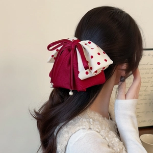 Barrette élégante avec nœud en satin rouge à pois et perles sur cheveux bruns