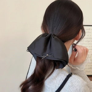 Elegant black satin bow hair claw clip with crystal accents shown on long hair