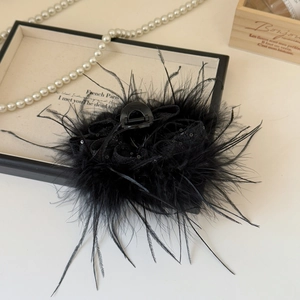 Détail de l'élégante pince à cheveux en plumes noires avec décor pailleté sur plateau