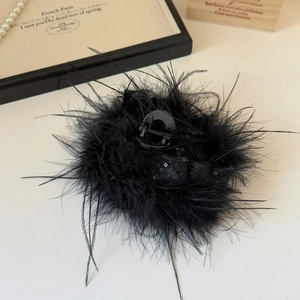 Détail d'une pince à cheveux en plumes noires avec sequins sur fond beige élégant