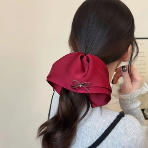 Elegant red satin bow hair clip with rhinestone accent for a chic ponytail look