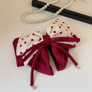 Détail du nœud papillon à pois rouges avec rubans bordeaux et breloques en perles
