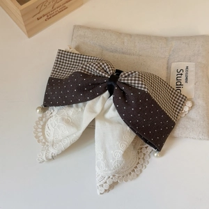 Close-up of French lace bow hair clip with embroidery texture and pearl pendant detail