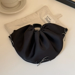 Detail view of a black satin claw clip featuring elegant rhinestone bow accents and pleats