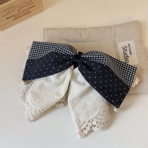 Detailed close-up of French lace bow hair clip with navy plaid and pearl accents