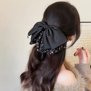 Elegant floral bow hair claw clip with black satin and hanging beads on wavy hair