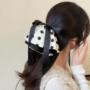 Détail d'un grand nœud à pois et ruban satin noir sur cheveux longs, vue arrière