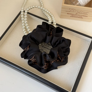 Détail d'un chouchou en satin avec bordure léopard sur un plateau de présentation
