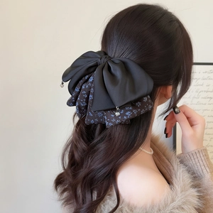Elegant floral bow hair clip with black satin and rhinestones on brunette wavy hair