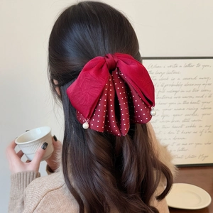 Elegant retro red polka dot bow hair claw clip with pearl pendants on wavy brown hair