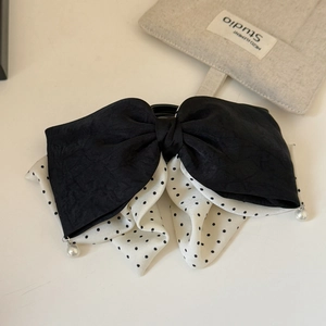 Detail view of double-layered polka dot bow hair claw with elegant pearl pendants